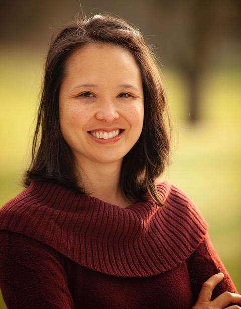 Khanh Pham, a Vietnamese-American woman smiles at the camera. She wears a sweater and has shoulder length hair.